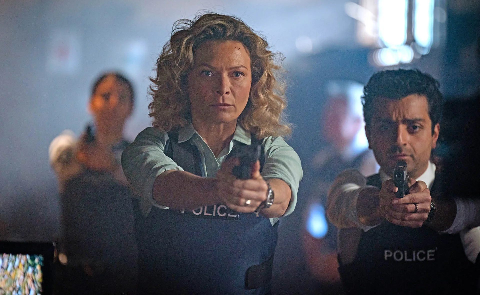 Detective Holly O'Rourke (Leeanna Walsman) points her gun at the camera. Detective Jarred Pines (Rahel Romahn) is standing behind her, also pointing a gun.