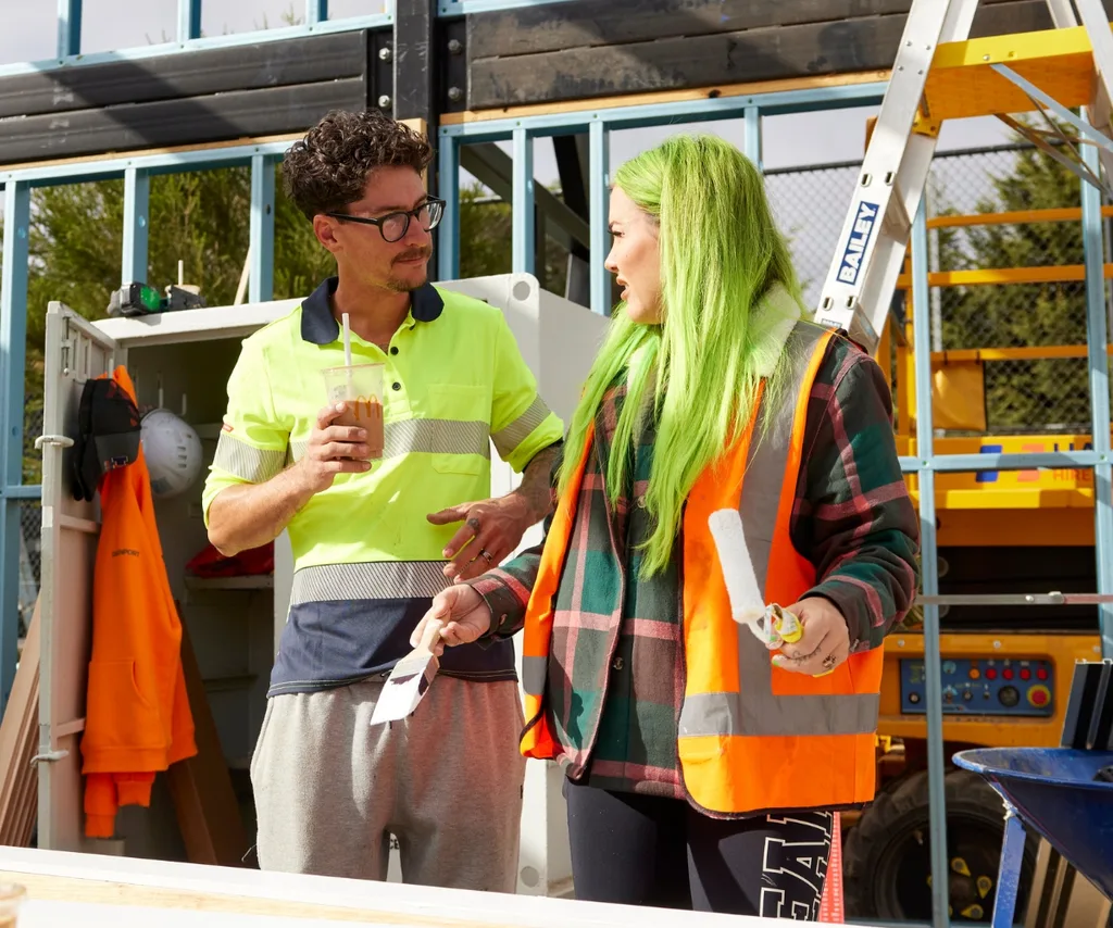 An image of Brad and Kylie from The Block in high vis clothing.