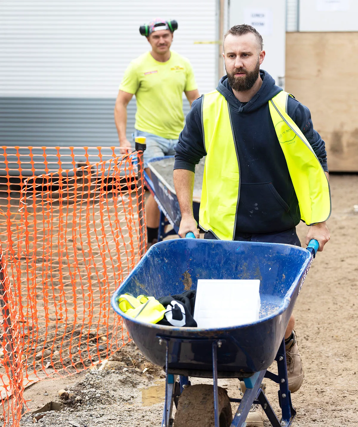 Ricky and Haydn on site pushing wheelbarrows, Ricky is behind Haydn