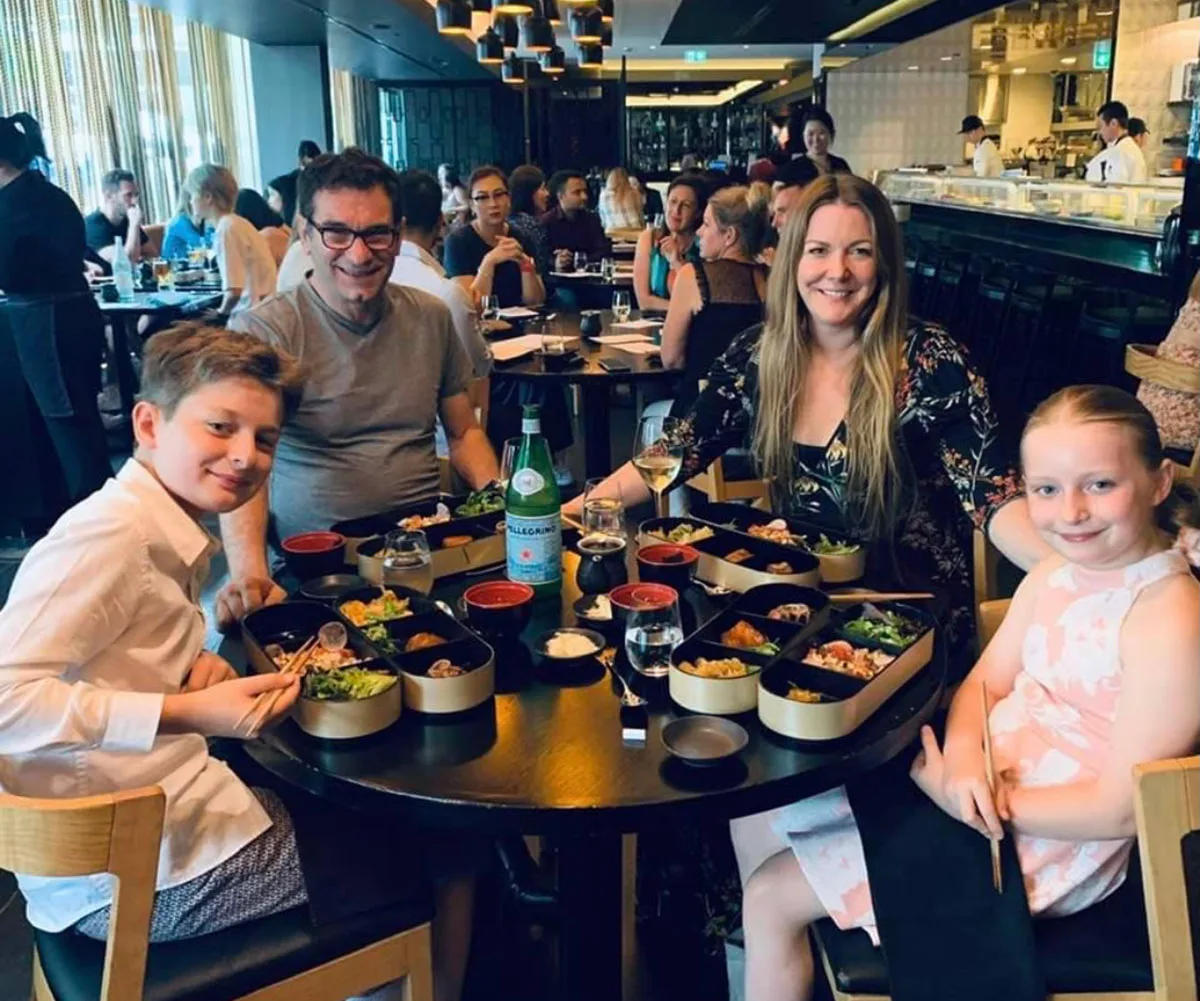 Peita, who created a tea towel-like product to save others thousands, sits at a busy restaurant with her husband and two children in front of fresh food