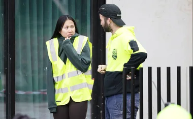 Mimi and Kristian rugged up in yellow hi vis looking stressed on site