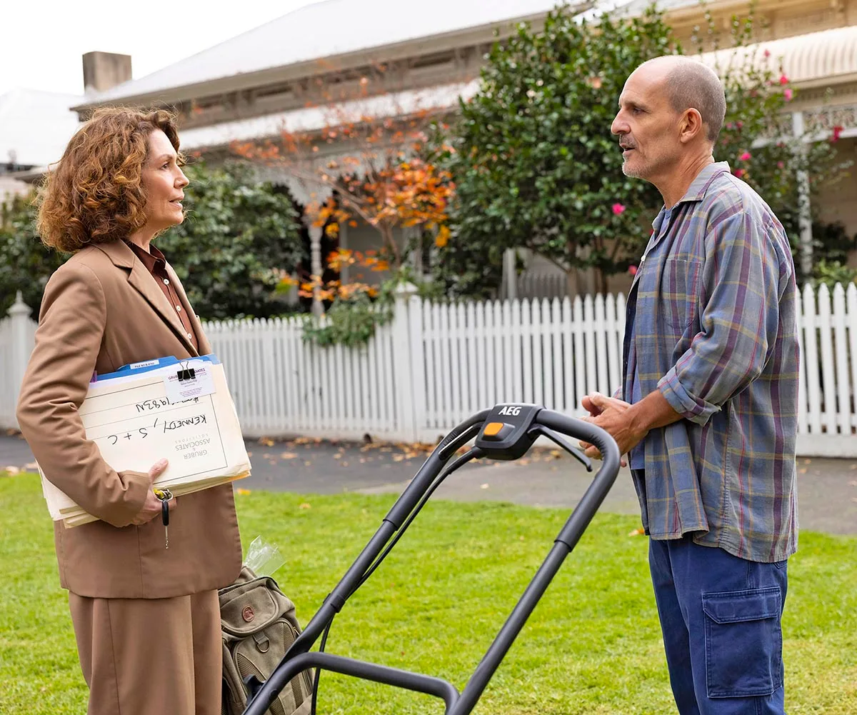 Carl Barron stands with Kitty Flanagan outside a suburban home in a still from the third season of Fisk.