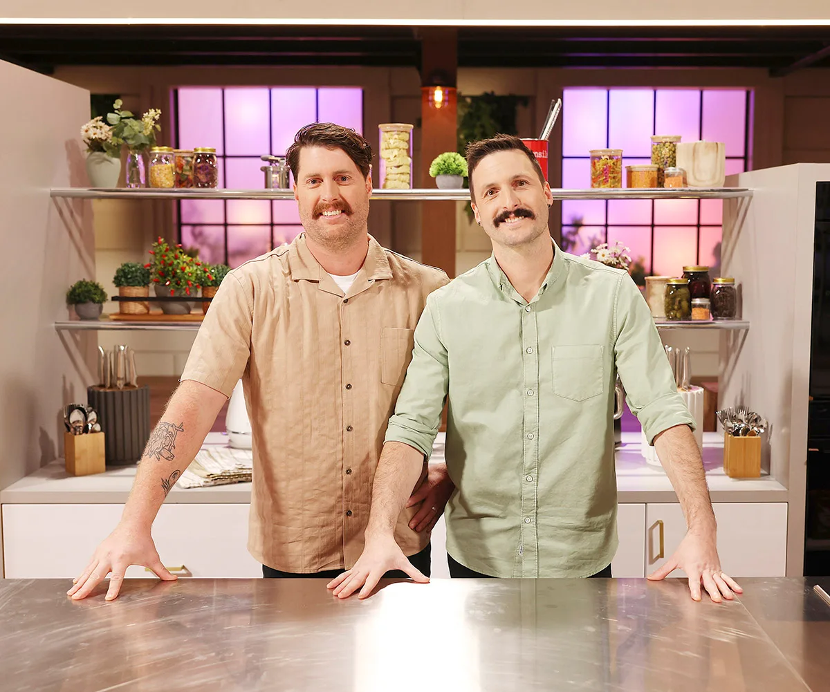 Rob and Liam stand behind a counter in Kitchen HQ, both smiling.