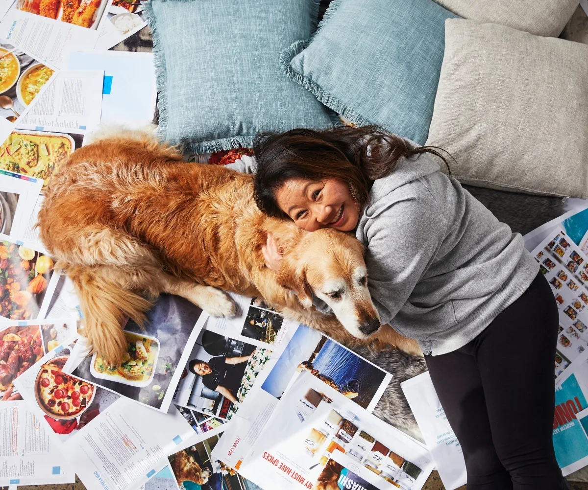 Nagi Maehashi lying next to her golden retriever Dozer on a pile of paper. 