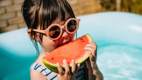 Small girl eating watermelon in summer