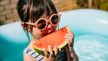 Small girl eating watermelon in summer