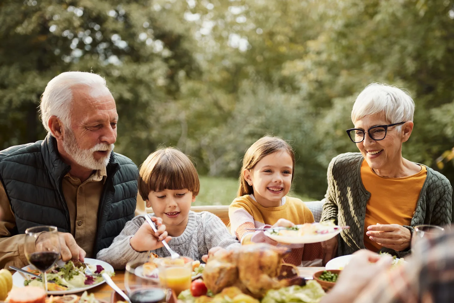 Two children eating outdoor meal with their grandparents