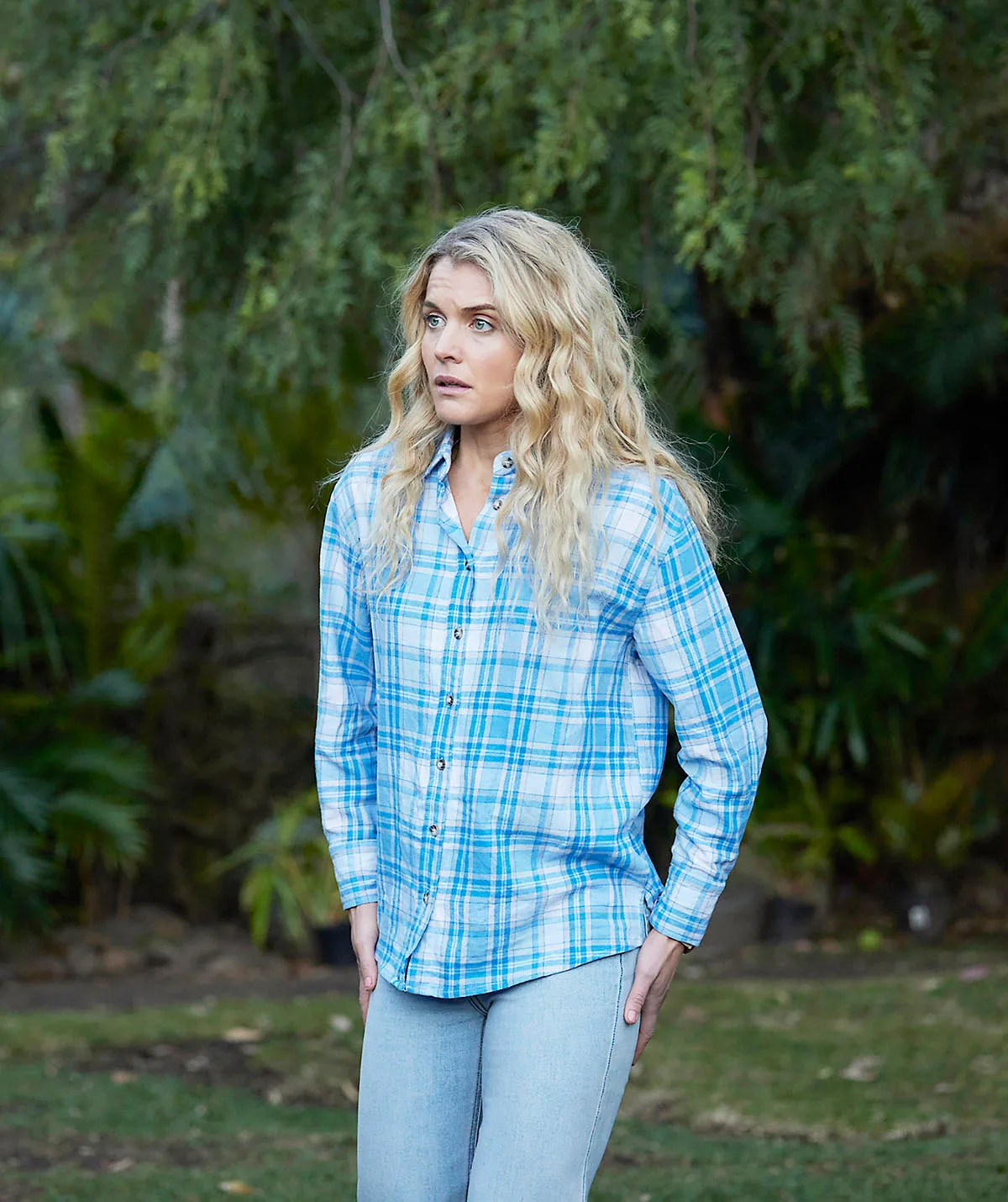 Bree stands in a blue flannelette shirt in a still from Home And Away