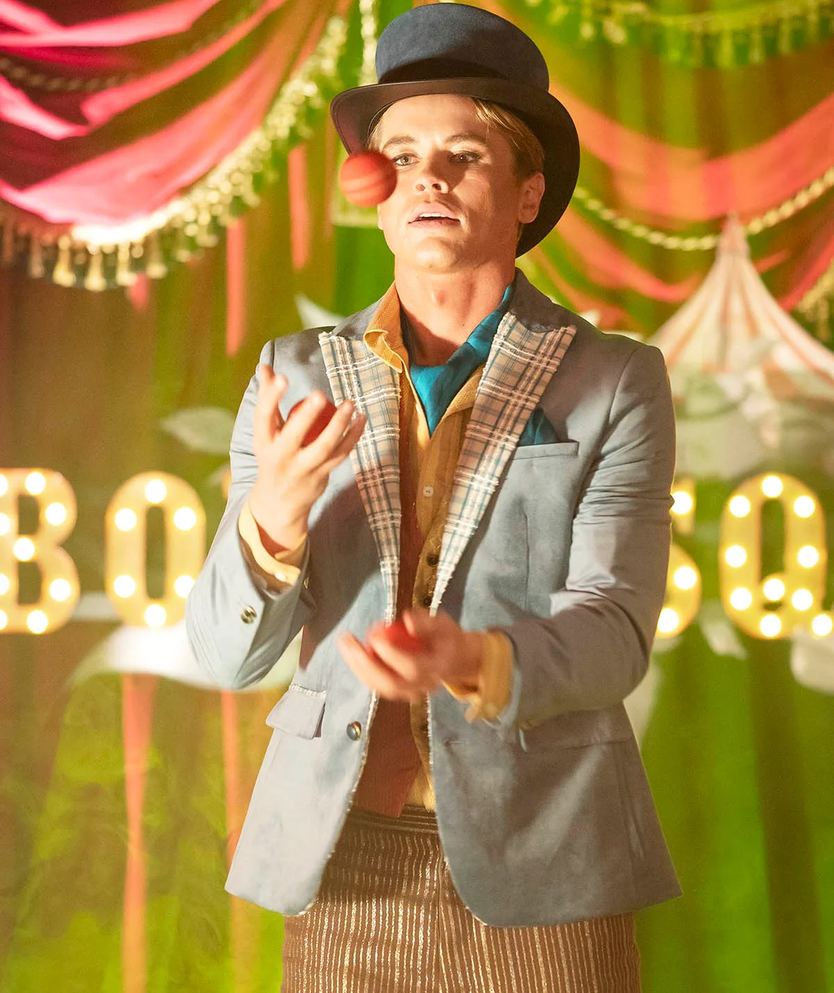 Byron juggling balls on stage at the Boylesque performance while wearing a top hat