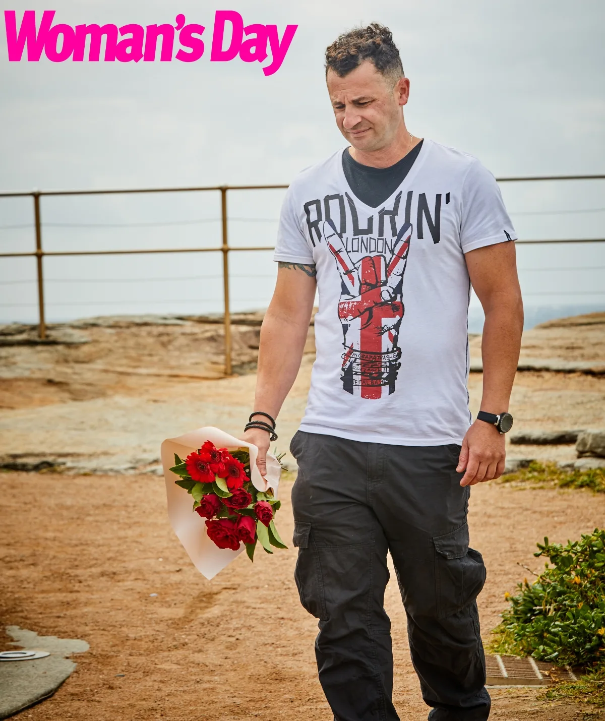 An image of Anthony Koletti holding a bunch of flowers on a cliff top.