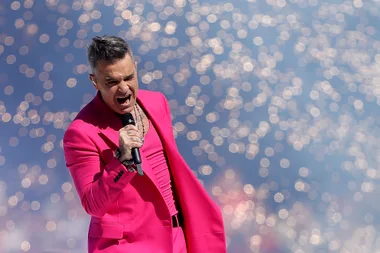 Robbie Williams on stage in pink suit