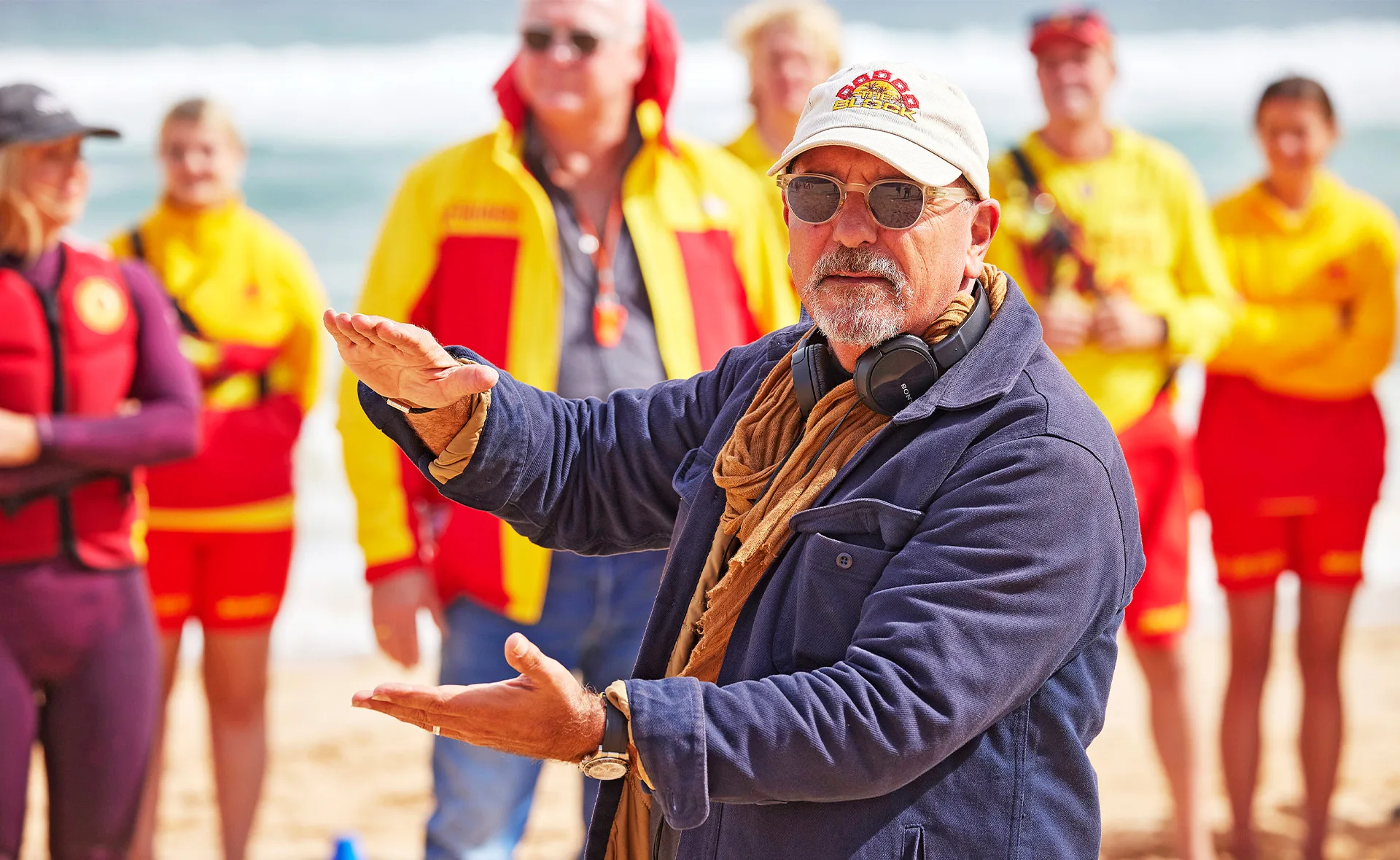 Julian Cress on the beach with lifeguards behind him