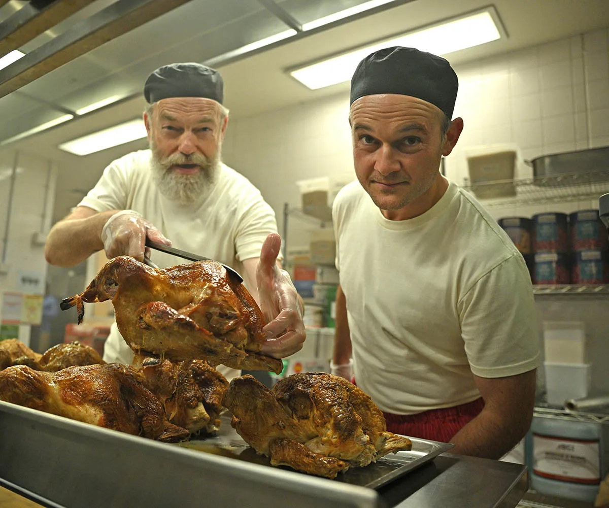 Hugo poses alongside actor Daniel Henshall in a jail's kitchen in a still from film How To Make Gravy