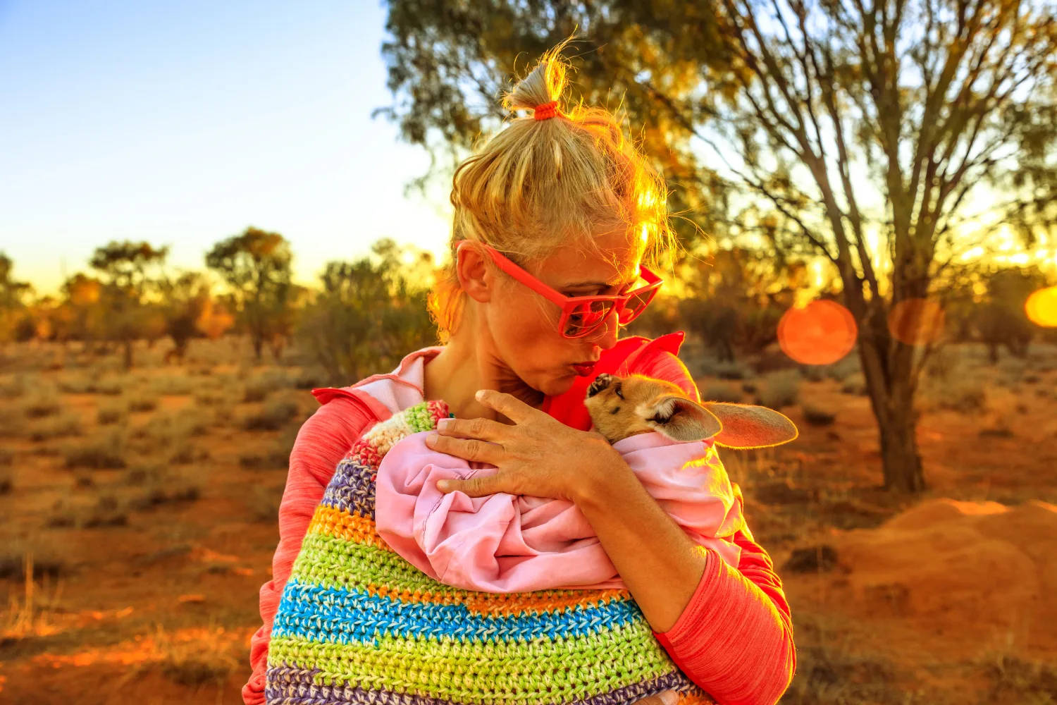 Woman holding joey in knitted pouch