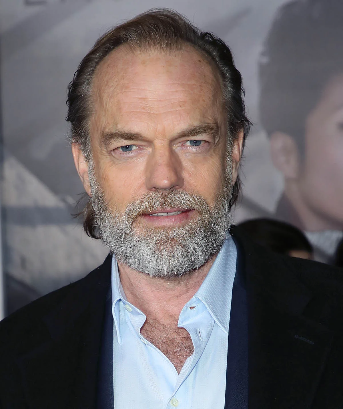 Hugo Weaving poses in a white shirt and jacket on the red carpet