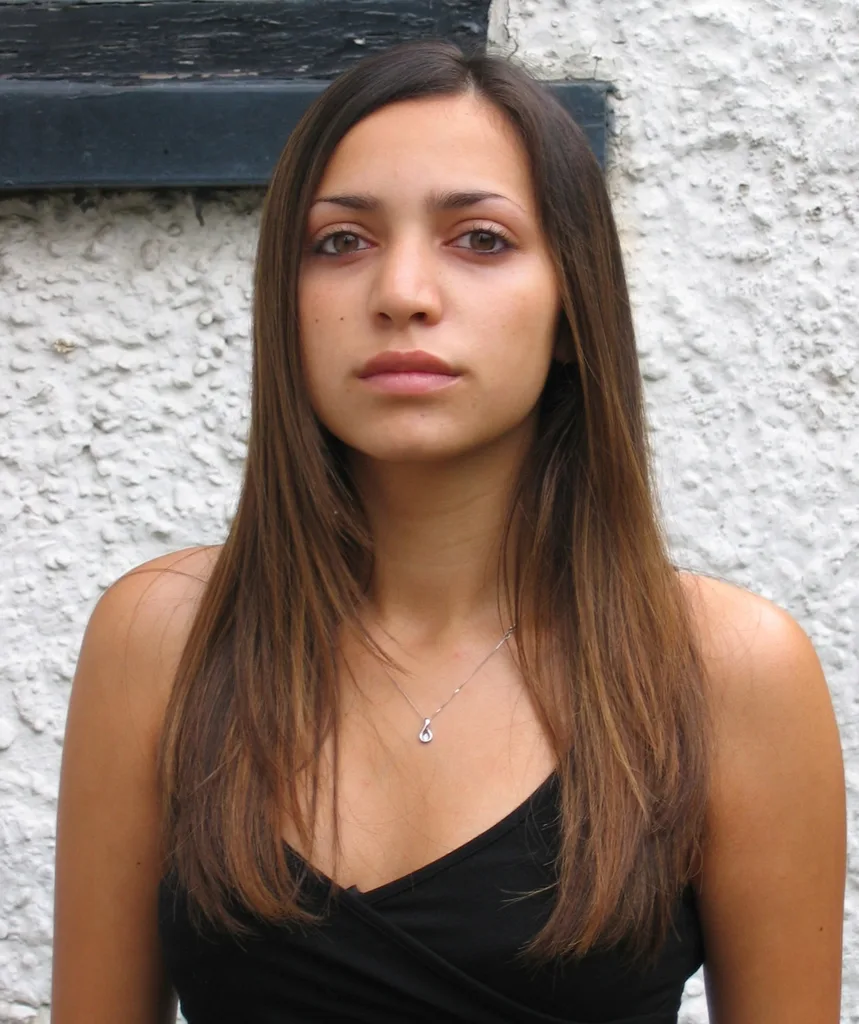 A brunette long-haired woman is looking at the camera.