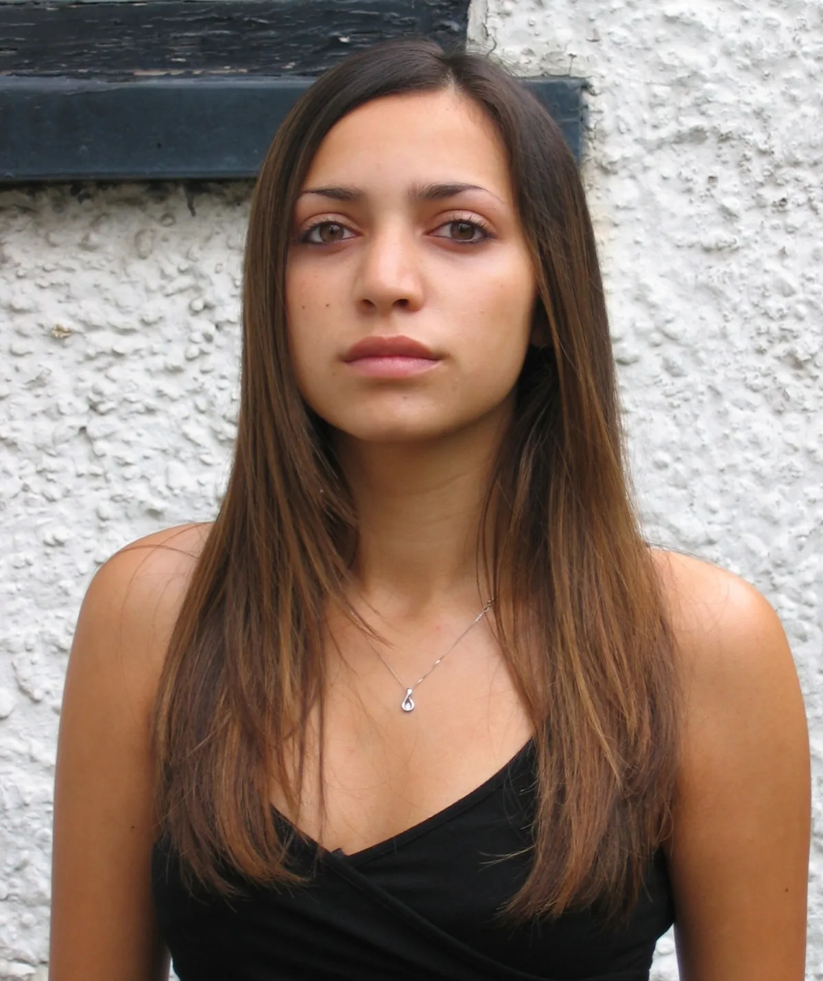 A brunette long-haired woman is looking at the camera. 