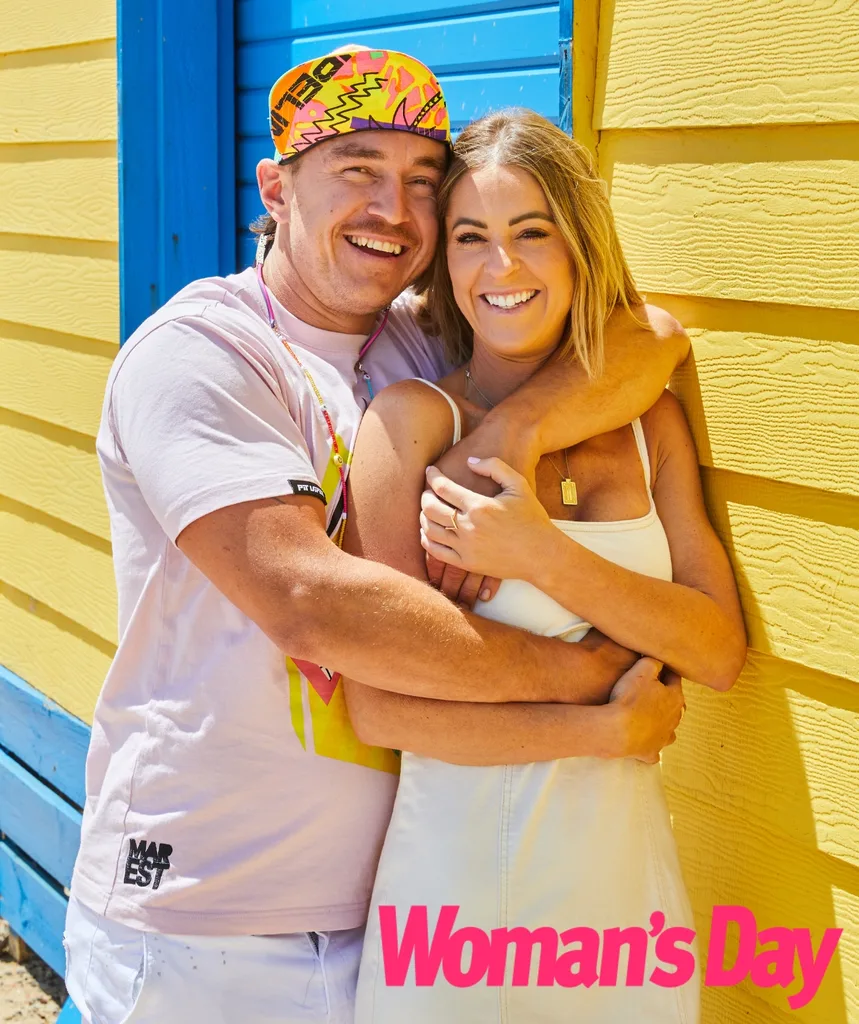 Ricky Recard and Erin Lee cuddle in front of beach houses.