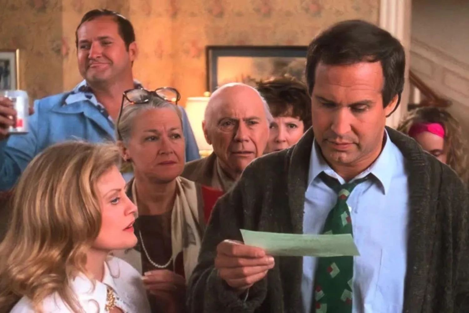 clark griswold looking at his christmas bonus surrounded by family in the national lampoons vacation