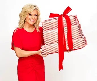 Emily Symons, who plays Marilyn in Home And Away, is wearing a red dress and holding a pile of presents.