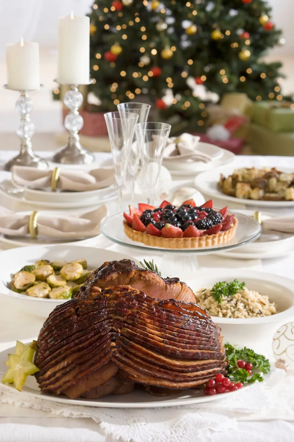 A tablespread with a ham, strawberry tart. 