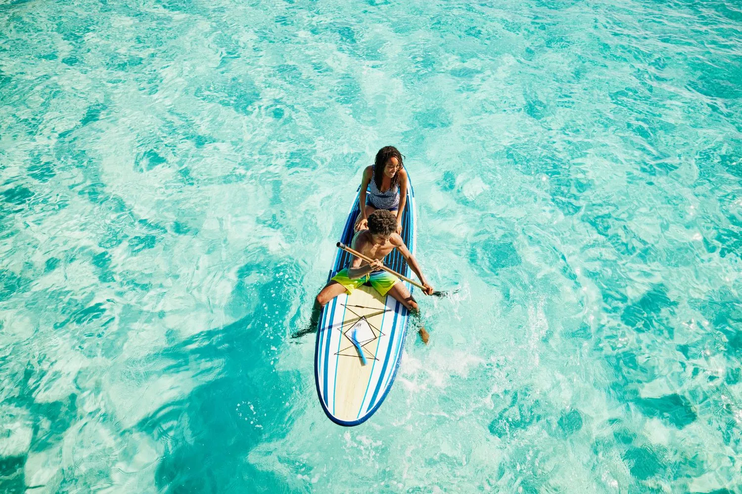 Two kids kayaking in blue water