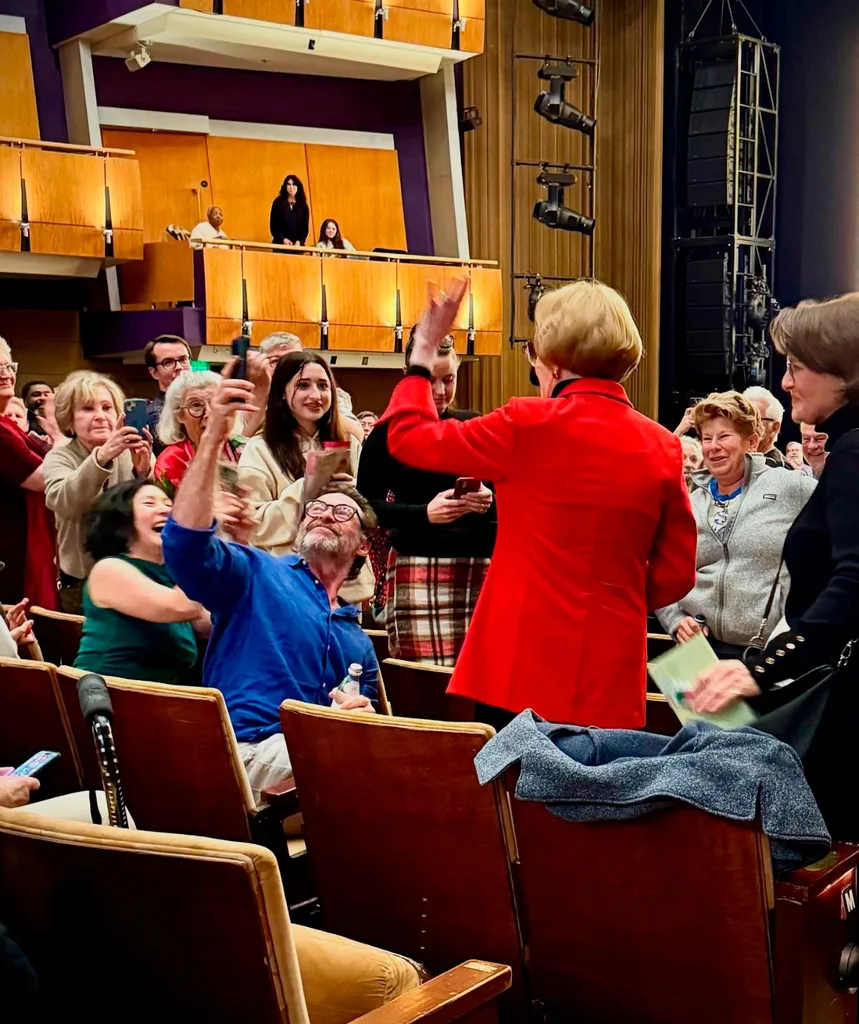 A large group of people are sitting and standing in a theatre.