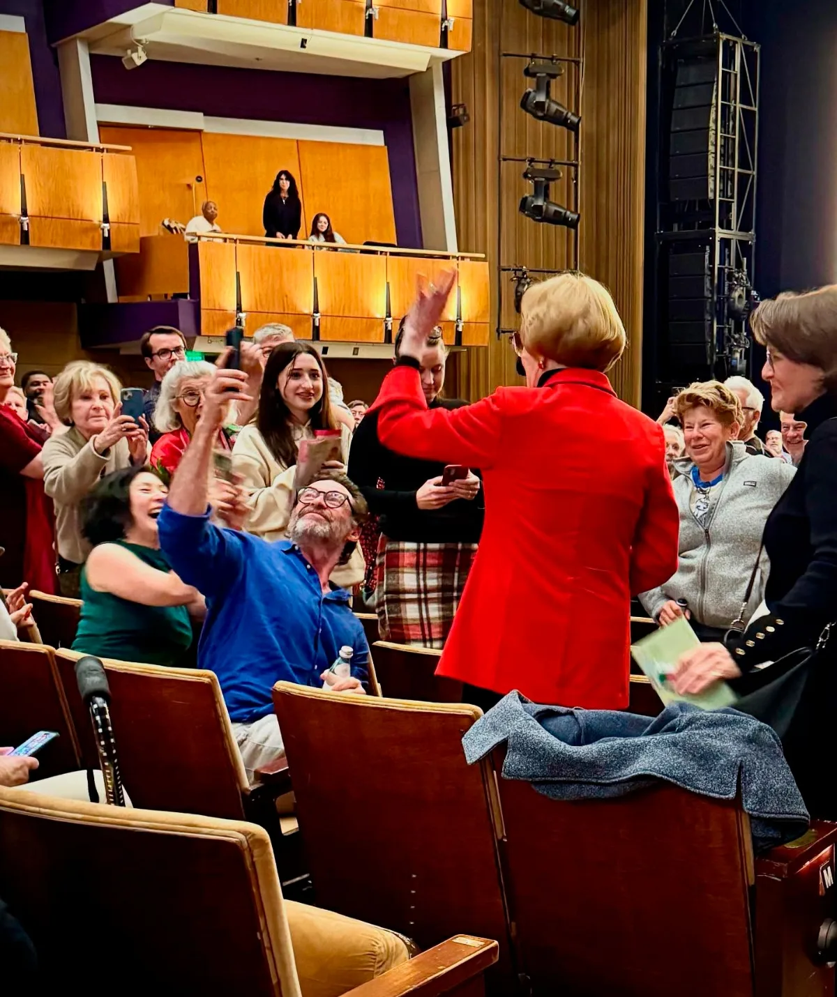 A large group of people are sitting and standing in a theatre.