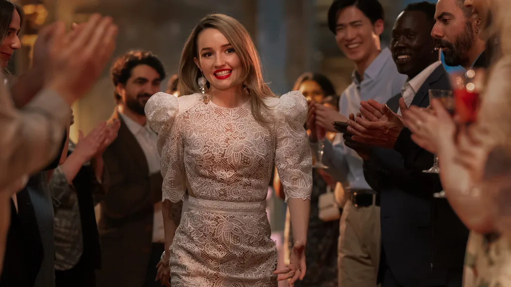 Kaitlyn Dever as Belle Gibson is dressed in a glamourous frock strutting amongst a cheering crowd