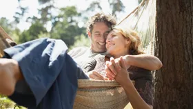 a happy couple sitting in a hammock
