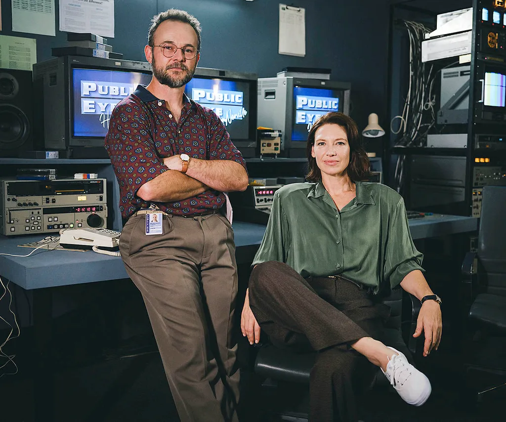 Daniel Henshall as producer Bill McFarlane and Anna Torv as Helen Norville pose in a 1980s-style newsroom for The Newsreader.