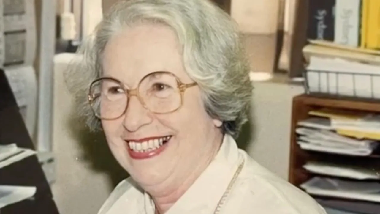Joan wearing glasses and pink lipstick, smiling