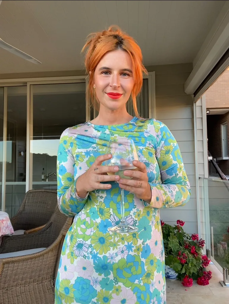 Bella in colourful dress, red hair and red lipstick looking happy and healthy