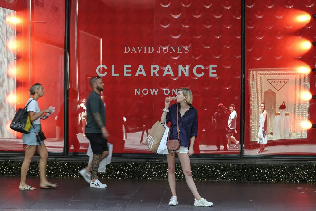 woman stands in front of retail sales sign