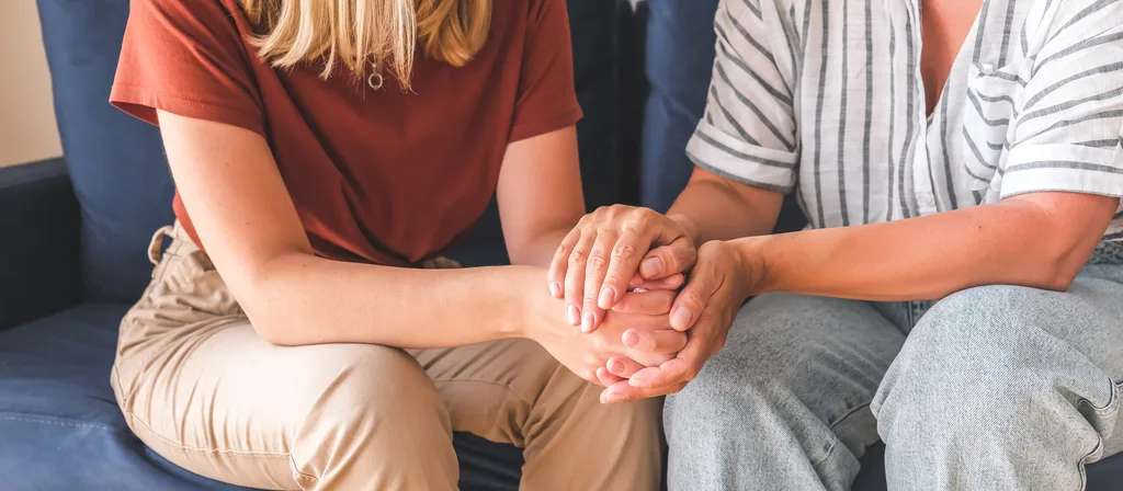 Two people holding each other's hands supportively