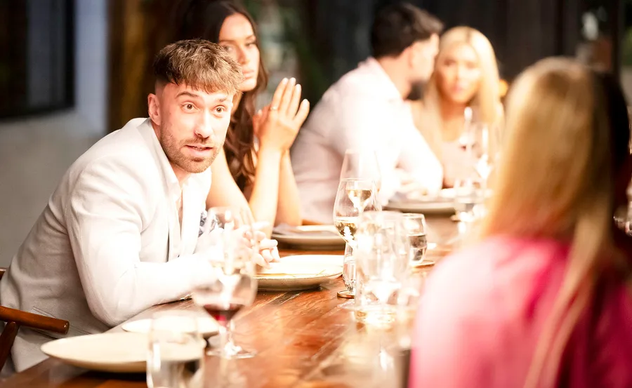 Billy speaking to Jamie (who only the back of is visible in a red dress) at the dinner table looking upset. Sierah sitting next to him looking disinterested.