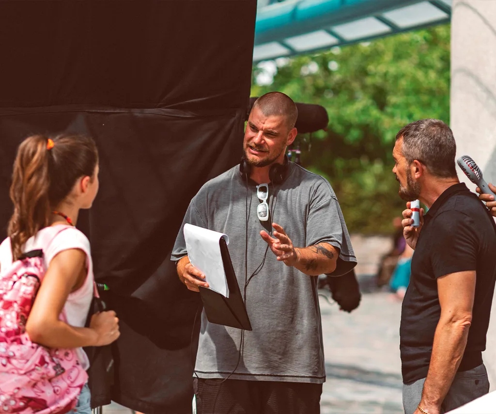 Rich is standing in between actor Antonio Banderas and an actress, directing them on the set of The Enforcer.