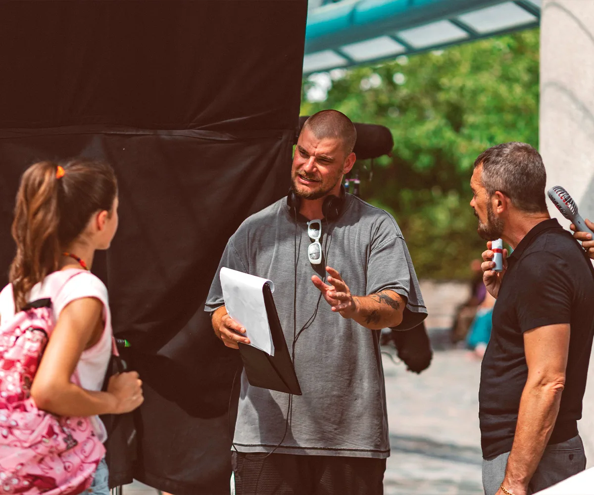 Rich is standing in between actor Antonio Banderas and an actress, directing them on the set of The Enforcer.
