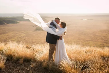 Jonathon and Hollie dressed as bride and groom embracing in a field after their country wedding