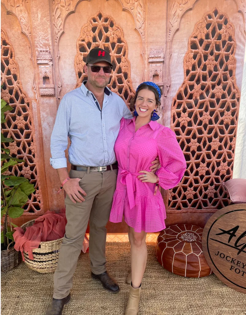 Jono wearing hat and glasses with Hollie in a bright pink dress at the country races