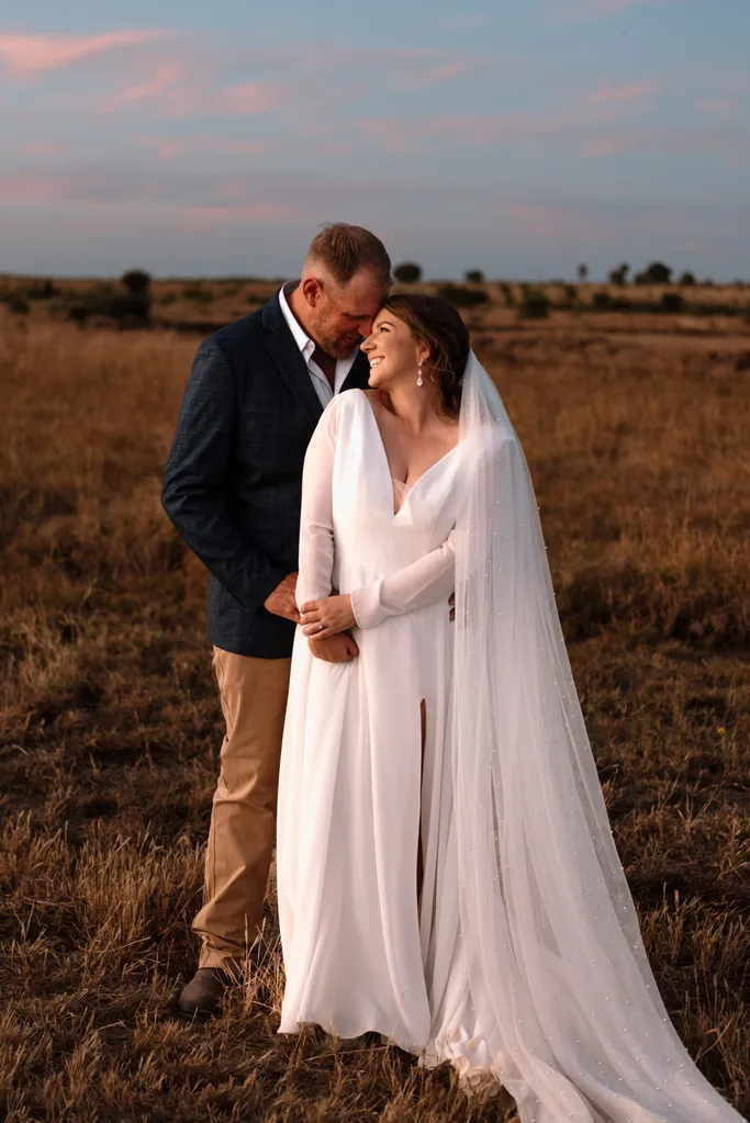 Jono and Hollie dressed as bride and groom staring into each other's eyes during their country wedding