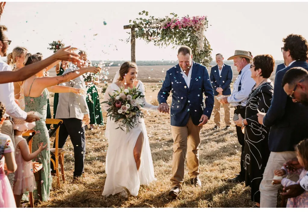 Hollie and Jono walking down the aisle as guests throw confetti during their country wedding
