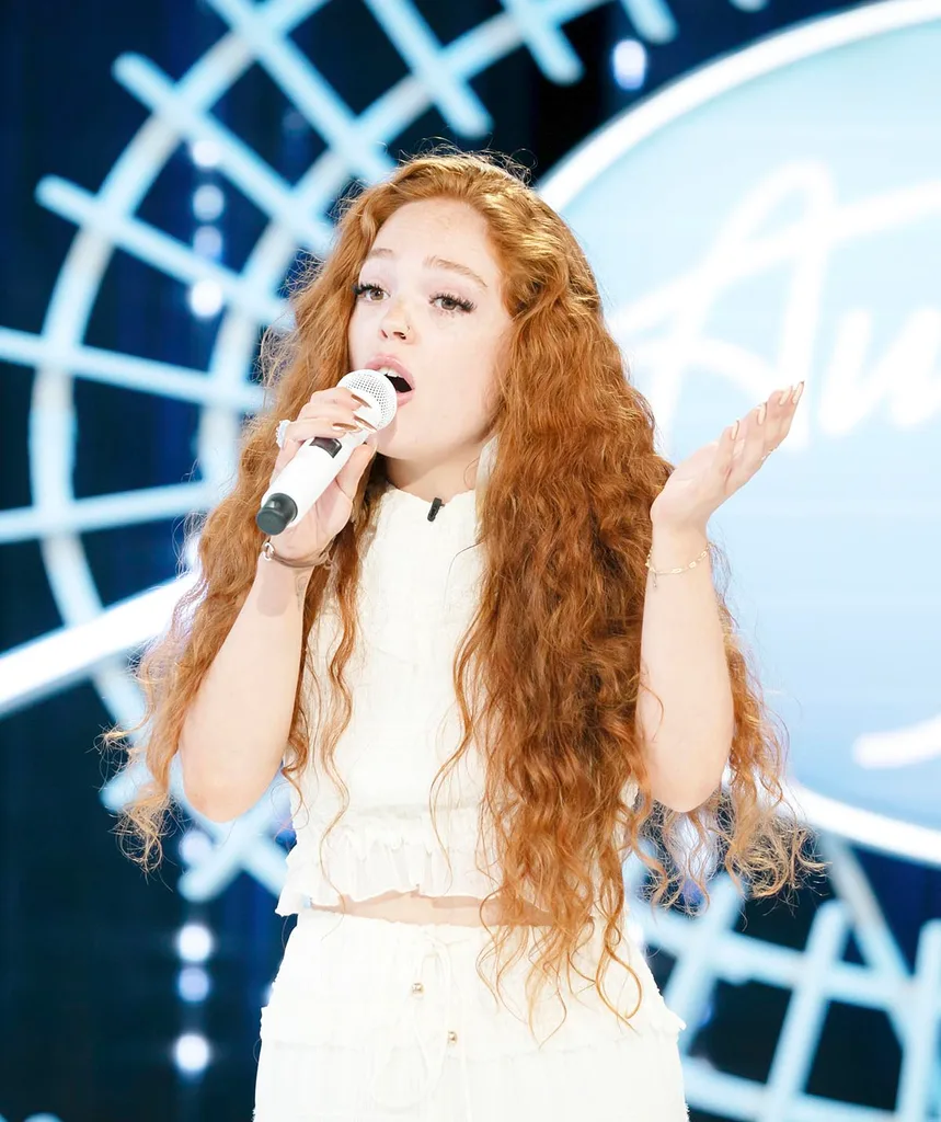 Jinja Blue, a woman with long red hair, sings on the Australian Idol audition stage