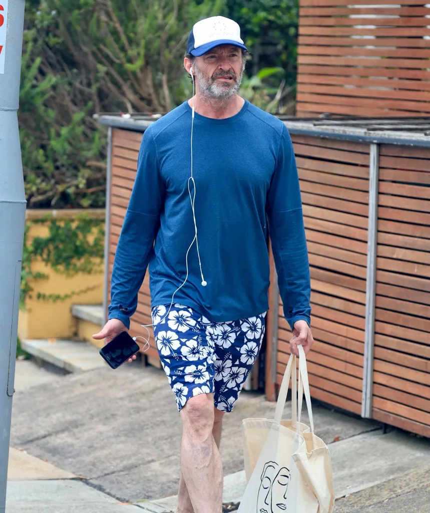 An image of a middle aged man with a cap on holding a shopping bag walking down the street.
