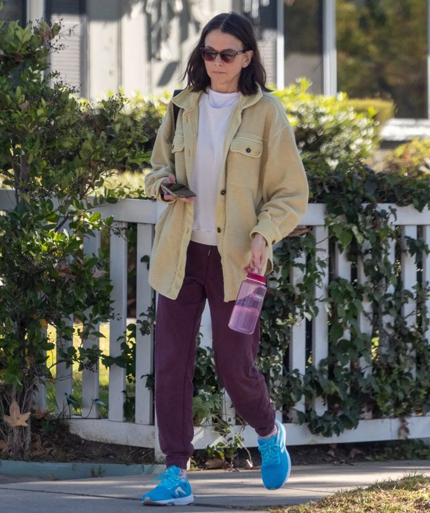 A woman in dark glasses walks down a street.