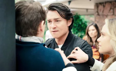 Leo has his hands up against Seb roughing him up as Krista tries to separate them and Fallon watches on in the background
