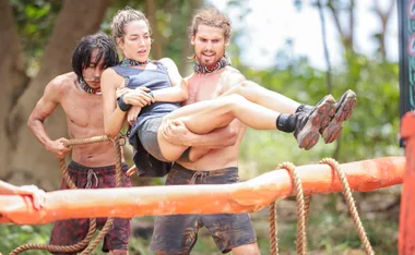 Kaelan carries Kate during a challenge on Australian Survivor while Myles stands behind them.