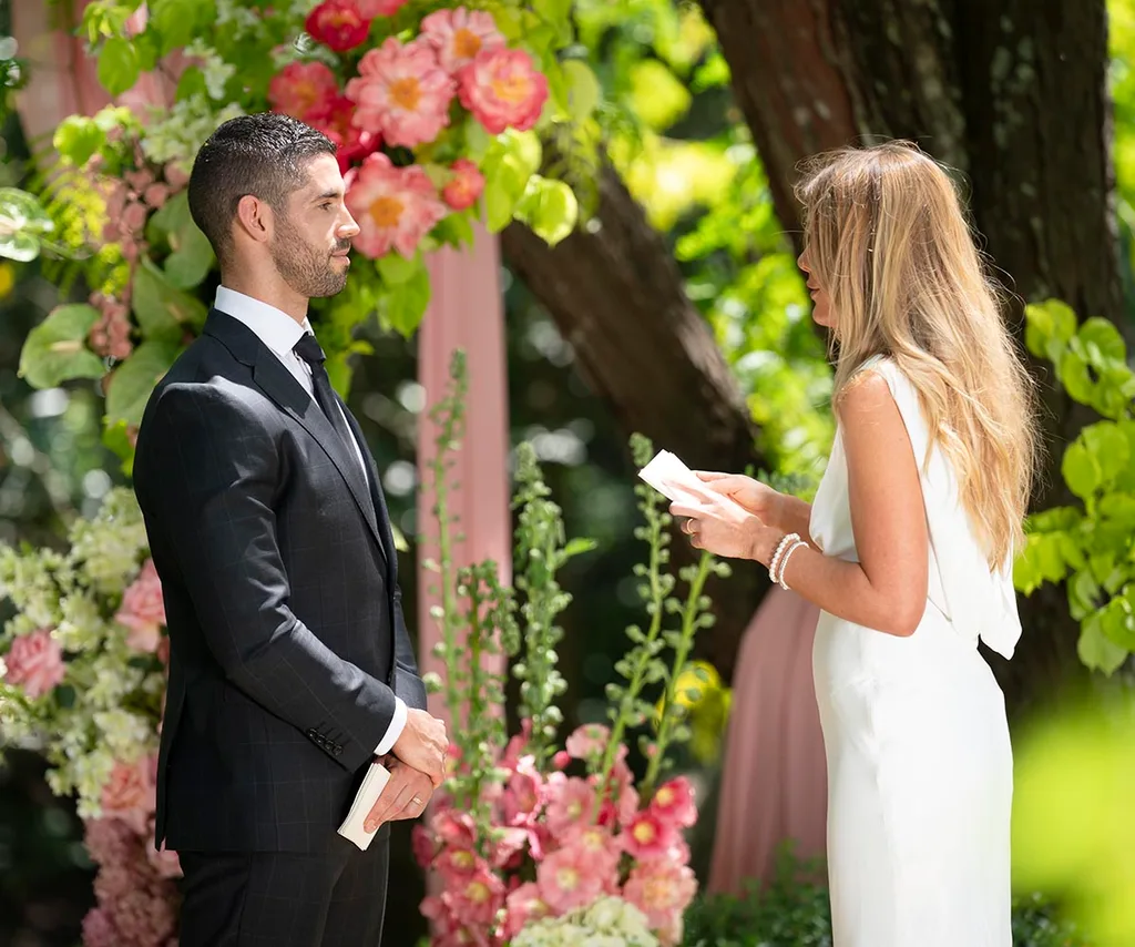 Ryan on the left and Jacqui on the right. Jacqui reads from her Final Vows cards as they stand in a garden.