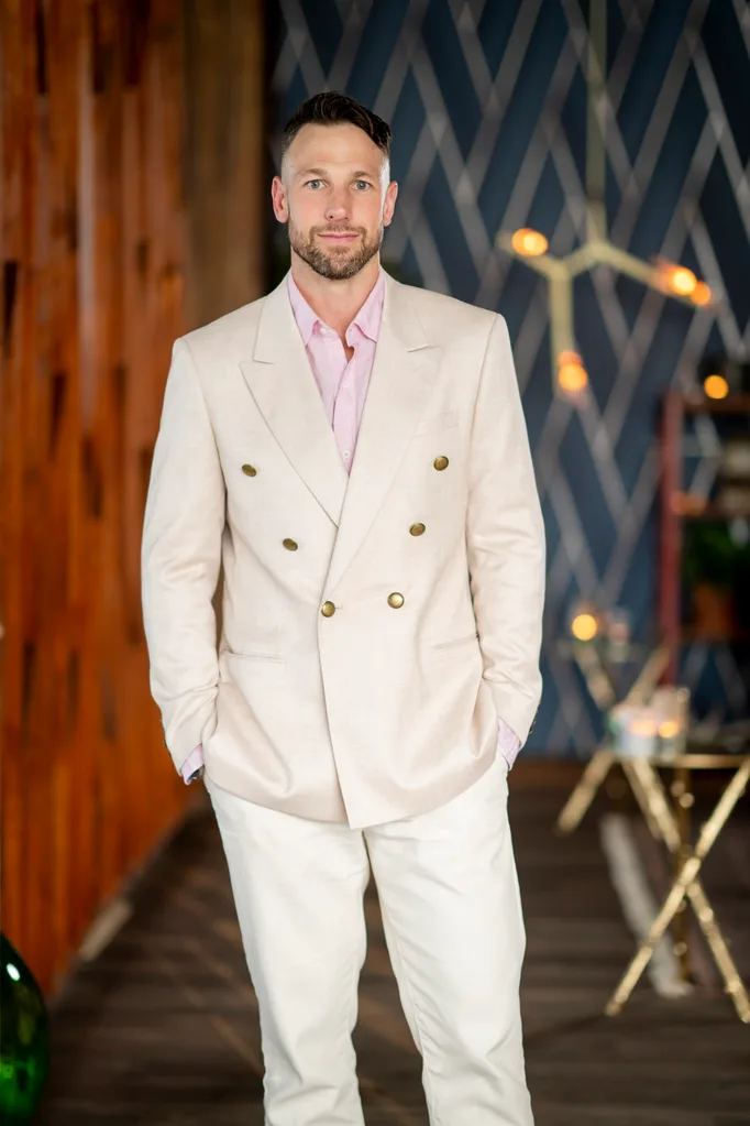 Jeff at the Dinner Party wearing a cream suit with a pink button up shirt.