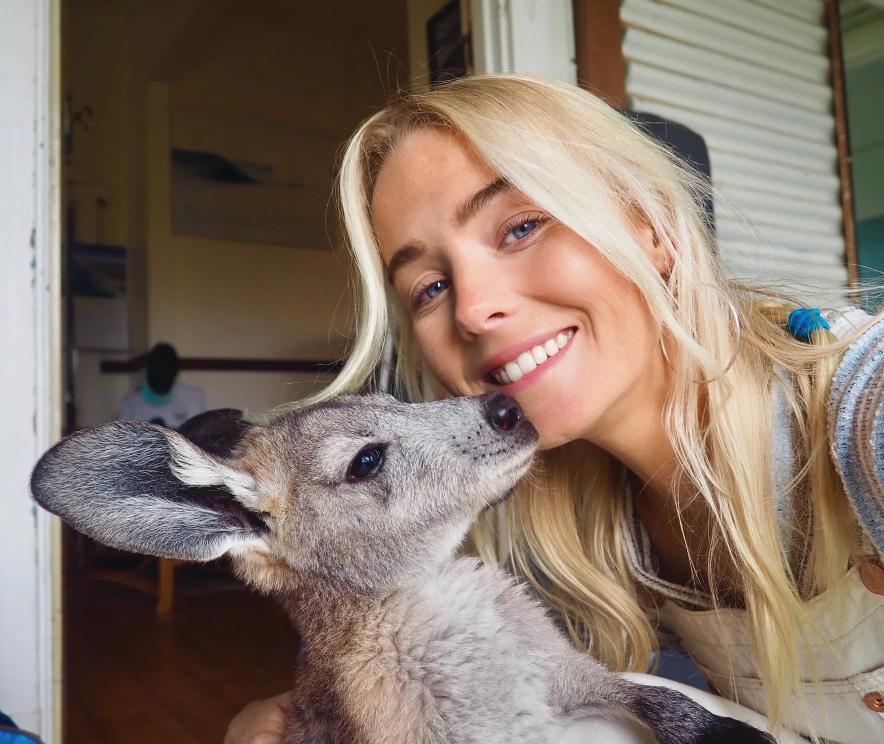 Blonde haired Brinkley leans in as Bunji the kangaroo kisses her cheek